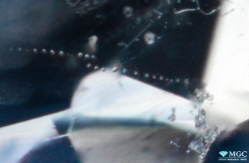 Цепочка газовых пузырьков, образовавшихся на месте разрушенного термообработкой включения бёмита. Режим просмотра - тёмнопольное освещение.