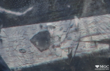 Разрушенное включение кальцита на фоне вуали буры, выполняющей открытую трещину в природном термообработанном сапфире. Режим просмотра - тёмнопольное освещение