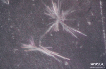 Characteristic mineral inclusions in synthetic amethyst of the “chrysanthemum” type, represented by a splice of needle-like crystals (probably wollastonite). View mode - dark lighting