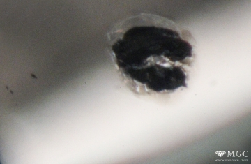 Mirror-type crack with a mirror reflection around the mineral inclusion of chrysolite in a natural diamond. View mode - dark field lighting