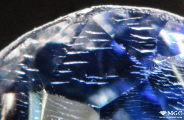 Near-surface cracks of the "fire signs" type on a synthetic sapphire cut. Synthesis method - Vernel method. View mode - dark lighting.