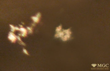Inclusions like "bread crumbs" in synthetic citrine. View mode - transmitted polarized light.